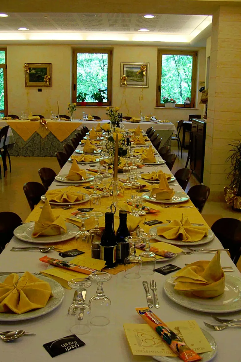 Tavolata apparecchiata nella sala grande della trattoria