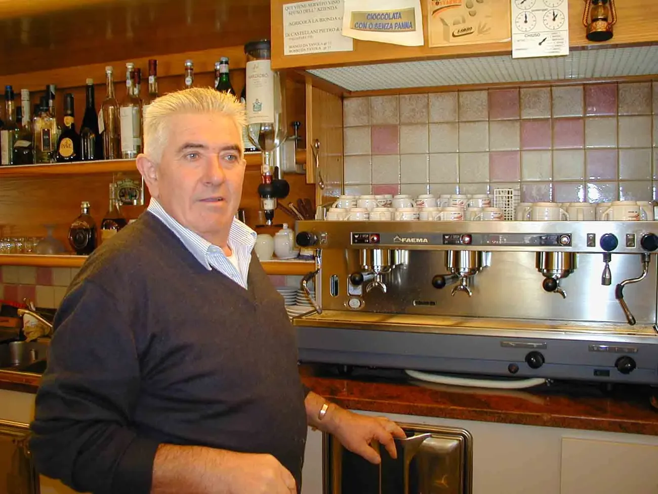 A man behind the trattoria's bar counter, next to the coffee machine
